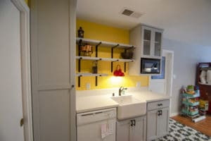 Gray cabinet kitchen remodel with shelves, barn sink and red sink light
